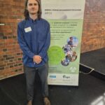 APEX 2024 Nicholas Davies 2 Young engineer Nicolas Davies of Beca stands infront of APEX banner